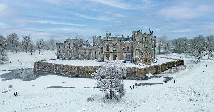 Raby Castle and deer park covered in snow on a bright blue day